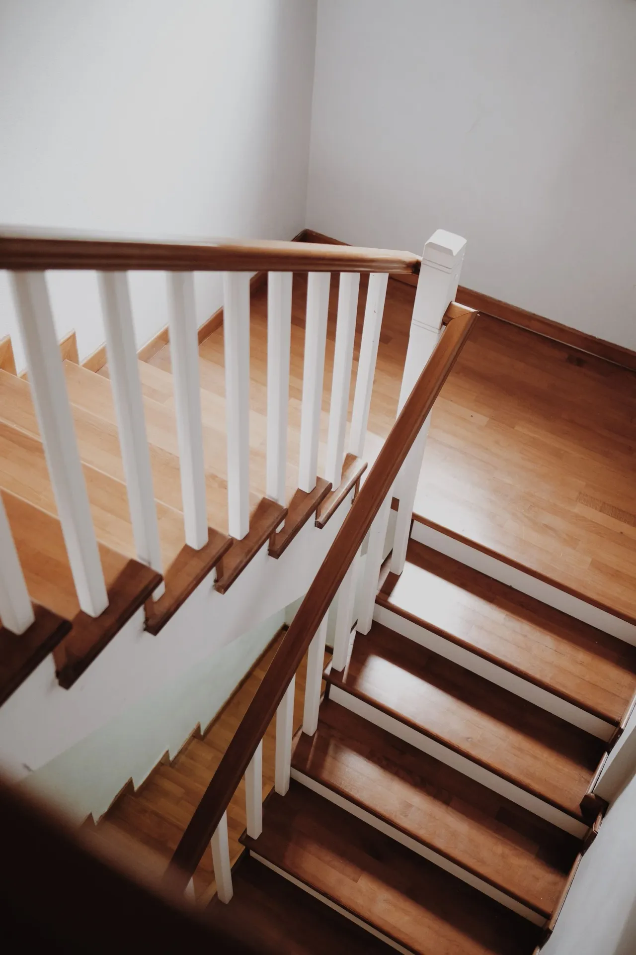 Un escalier tournant aux marches en chêne et à la rampe blanche, vu d'en haut